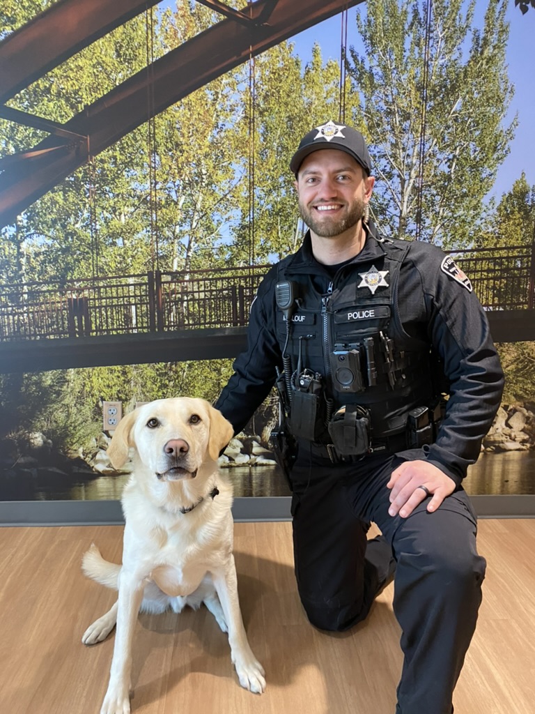 Harry Maalouf in uniform, kneeling beside a yellow Labrador, during his years in law enforcement